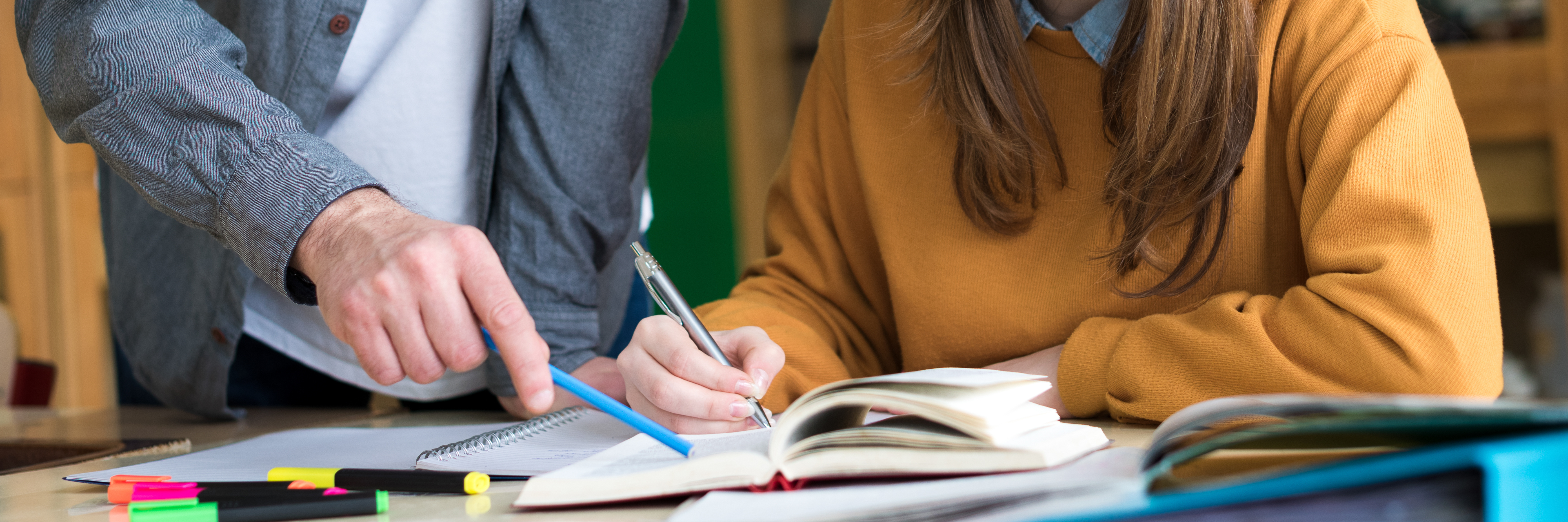 Teacher helping student with writing in classroom